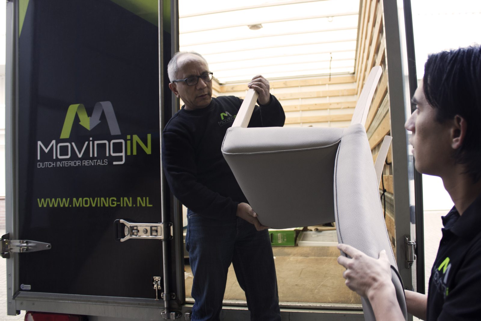 Twee collega's laden een stoel in de bakwagen